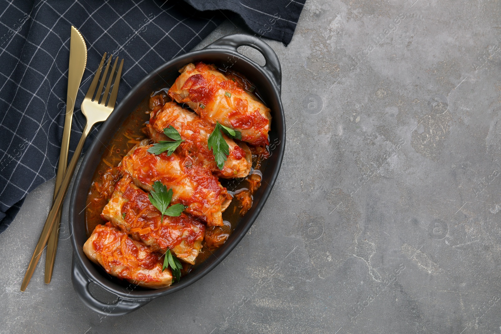 Photo of Delicious stuffed cabbage rolls cooked with tomato sauce on grey table, flat lay. Space for text
