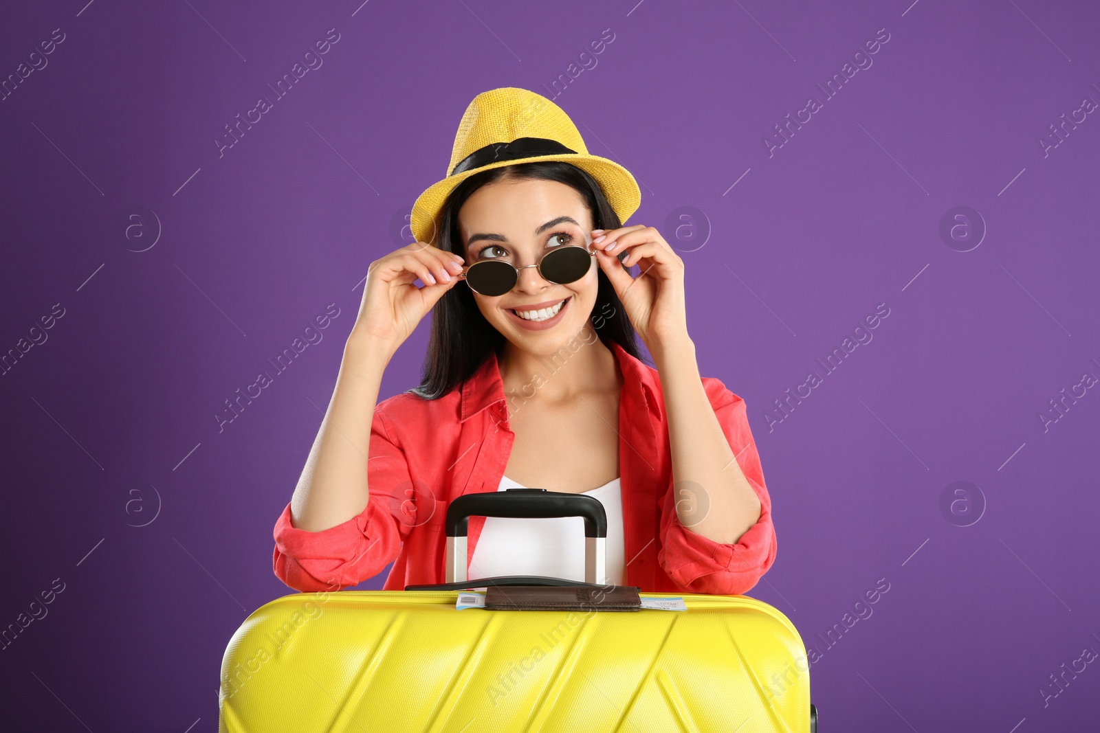 Photo of Beautiful woman with suitcase for summer trip on purple background. Vacation travel