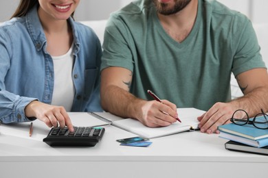 Young couple discussing family budget at table indoors, closeup