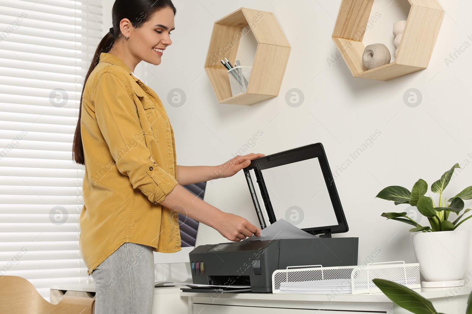 Photo of Woman using modern printer at workplace indoors