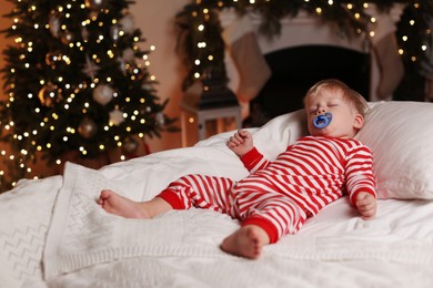 Photo of Baby in Christmas pajamas sleeping on bed indoors. Space for text