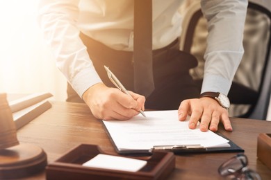 Image of Lawyer working with document at wooden table in office, closeup