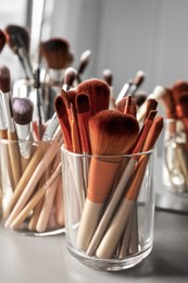 Set of professional makeup brushes near mirror on grey table