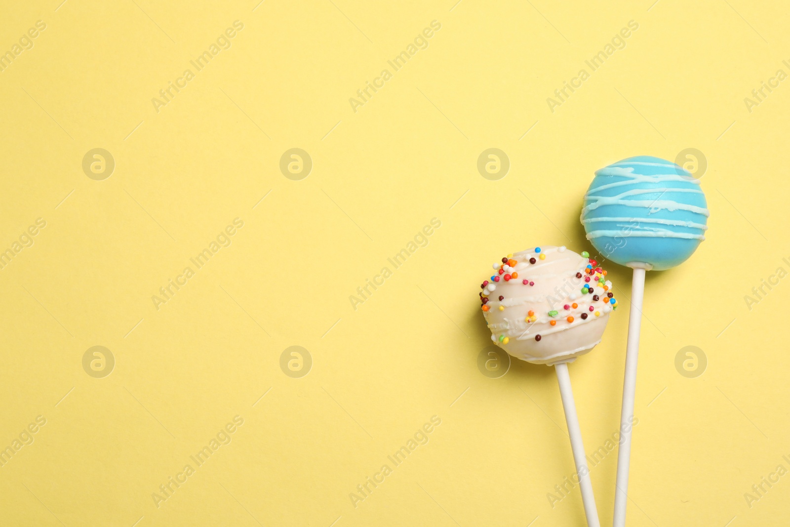 Photo of Bright delicious cake pops on color background, flat lay. Space for text