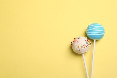 Bright delicious cake pops on color background, flat lay. Space for text