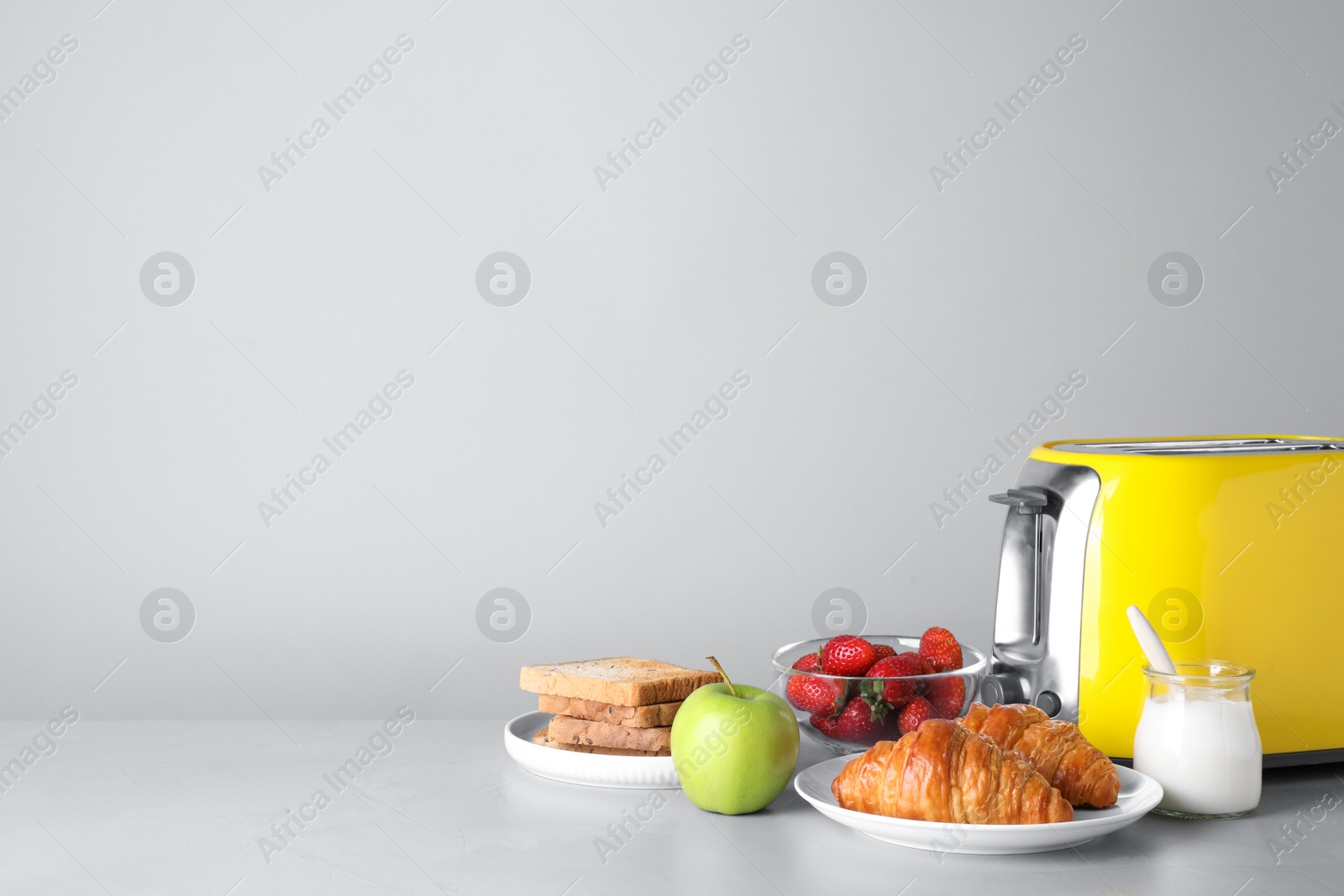 Photo of Healthy breakfast and modern toaster on light grey table, space for text