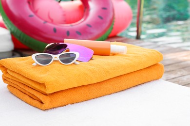 Beach towels, sunglasses and sunscreen on sunbed near outdoor swimming pool. Luxury resort