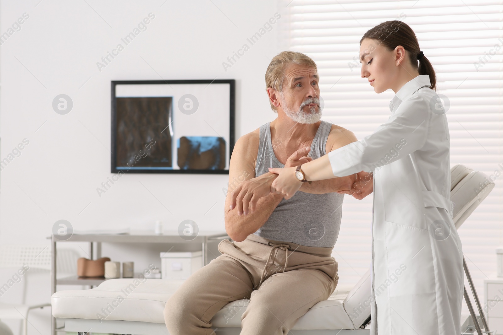 Photo of Orthopedist examining patient with injured arm in clinic