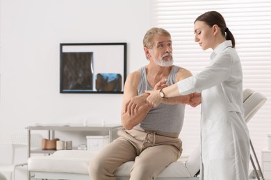 Orthopedist examining patient with injured arm in clinic