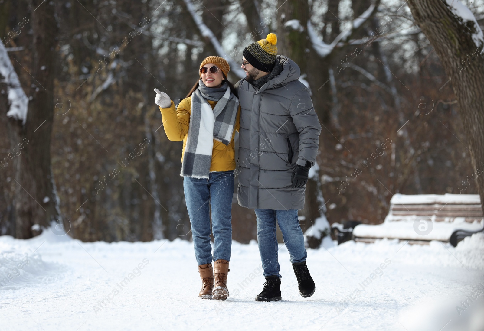 Photo of Happy young couple walking in snowy park on winter day