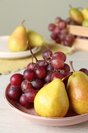Fresh ripe grapes and pears on white wooden table