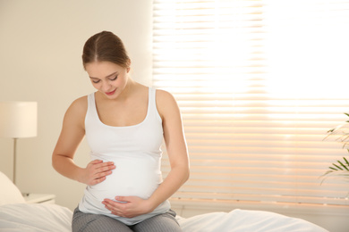Photo of Young pregnant woman on bed at home. Space for text