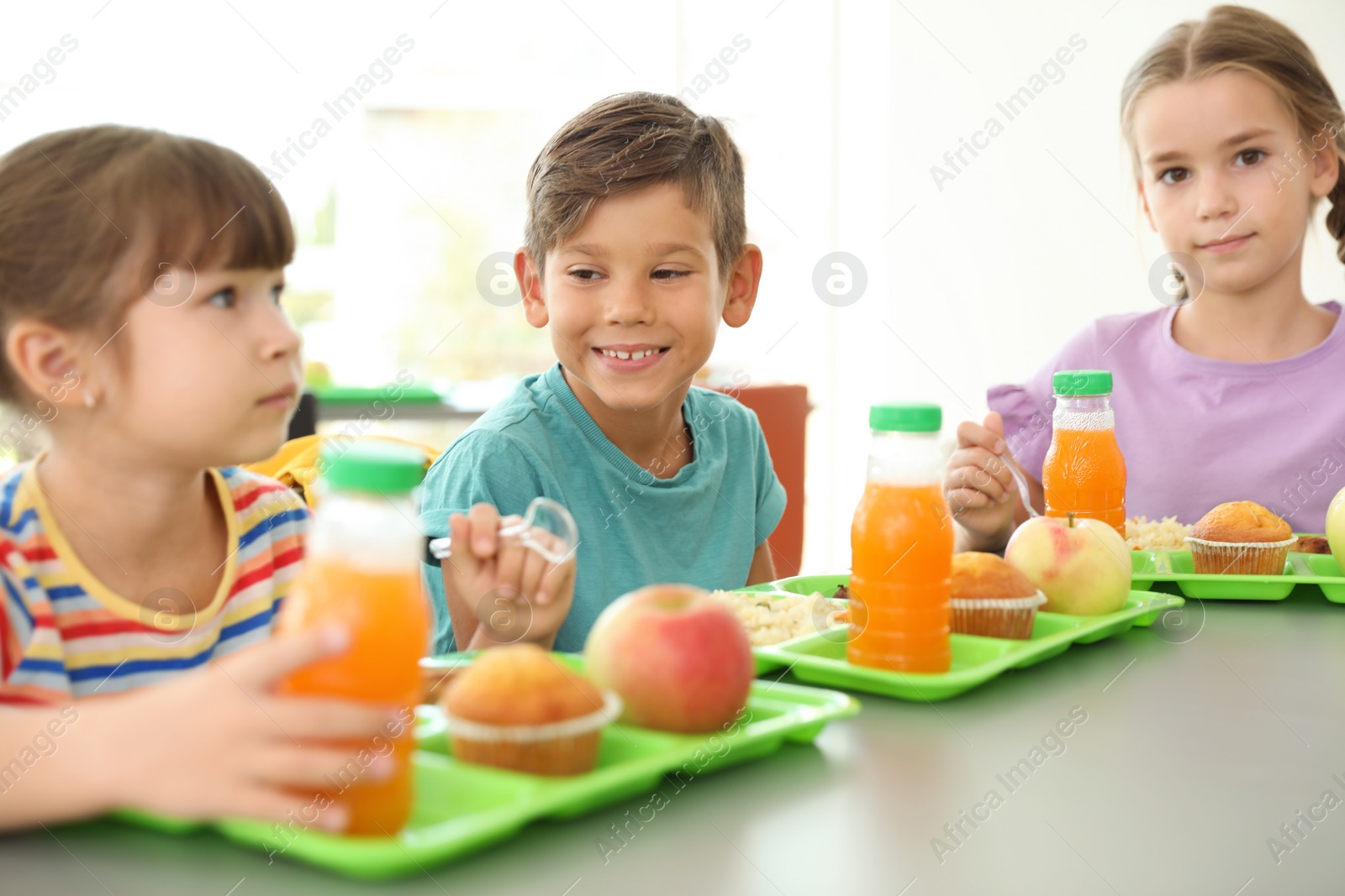 Photo of Children sitting at table and eating healthy food during break at school