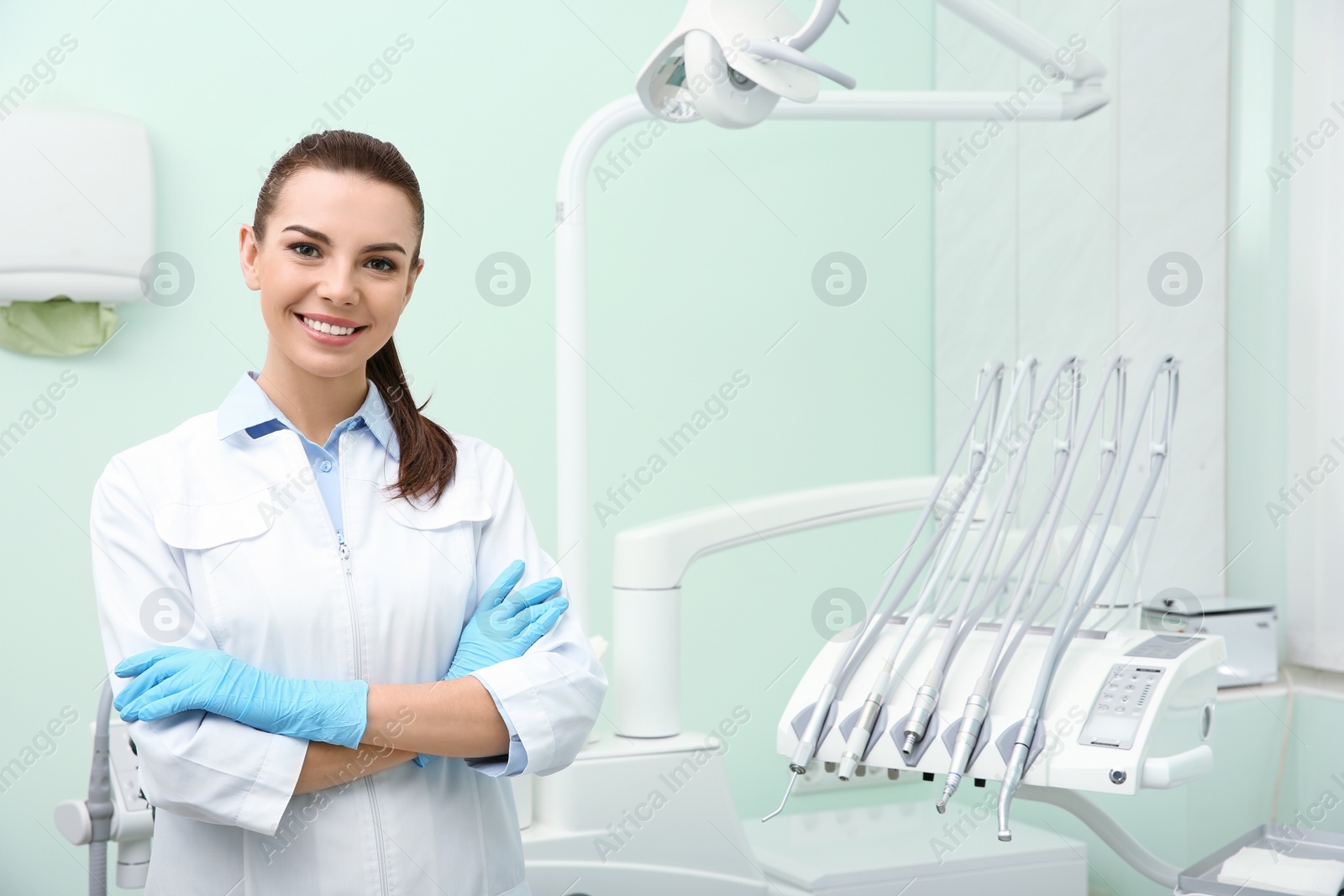 Photo of Young female dentist in white coat at workplace. Space for text