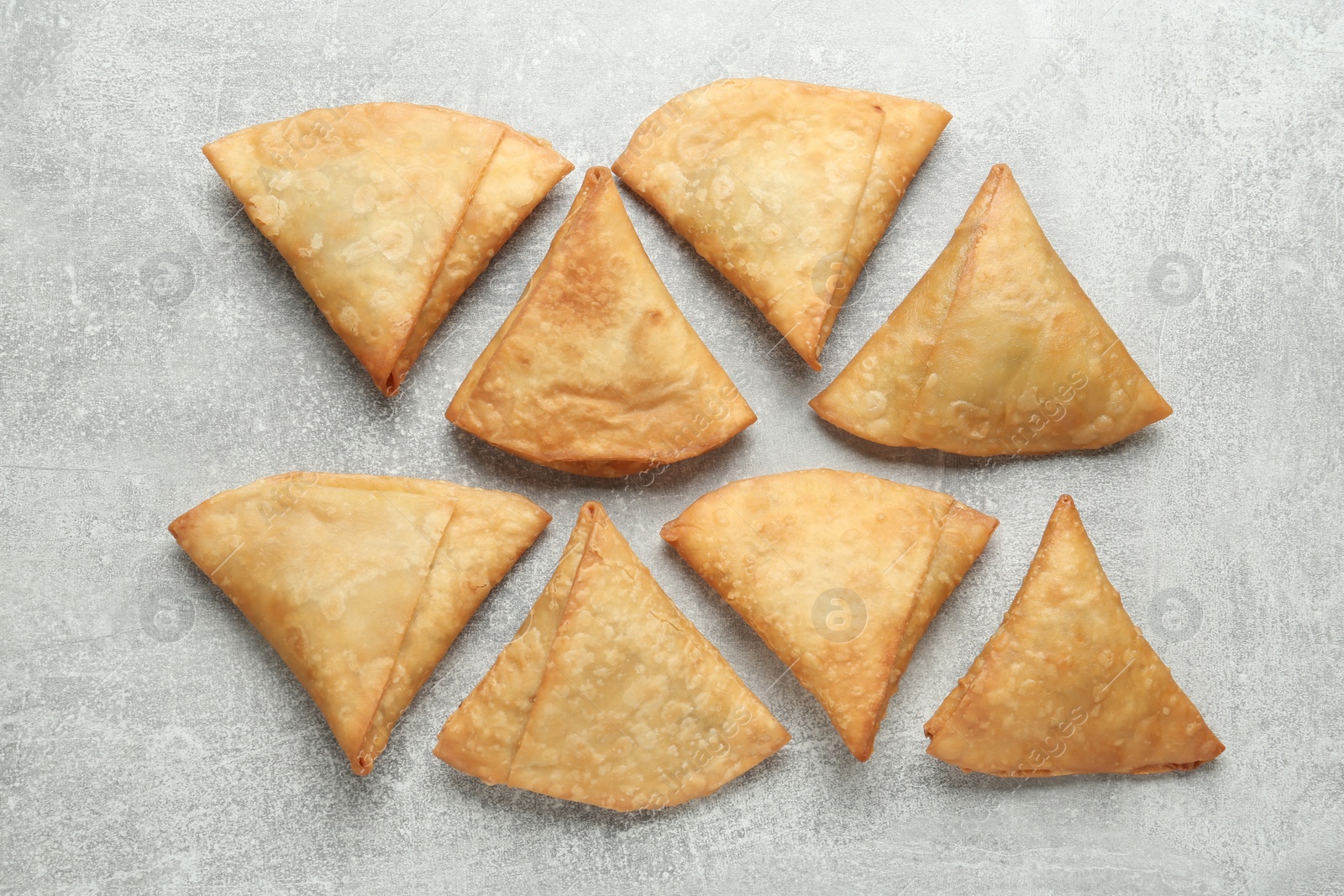 Photo of Fresh delicious crispy samosas on grey table, flat lay