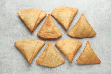 Photo of Fresh delicious crispy samosas on grey table, flat lay