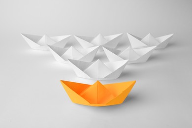 Photo of Orange paper boat among others on white background. Leadership concept
