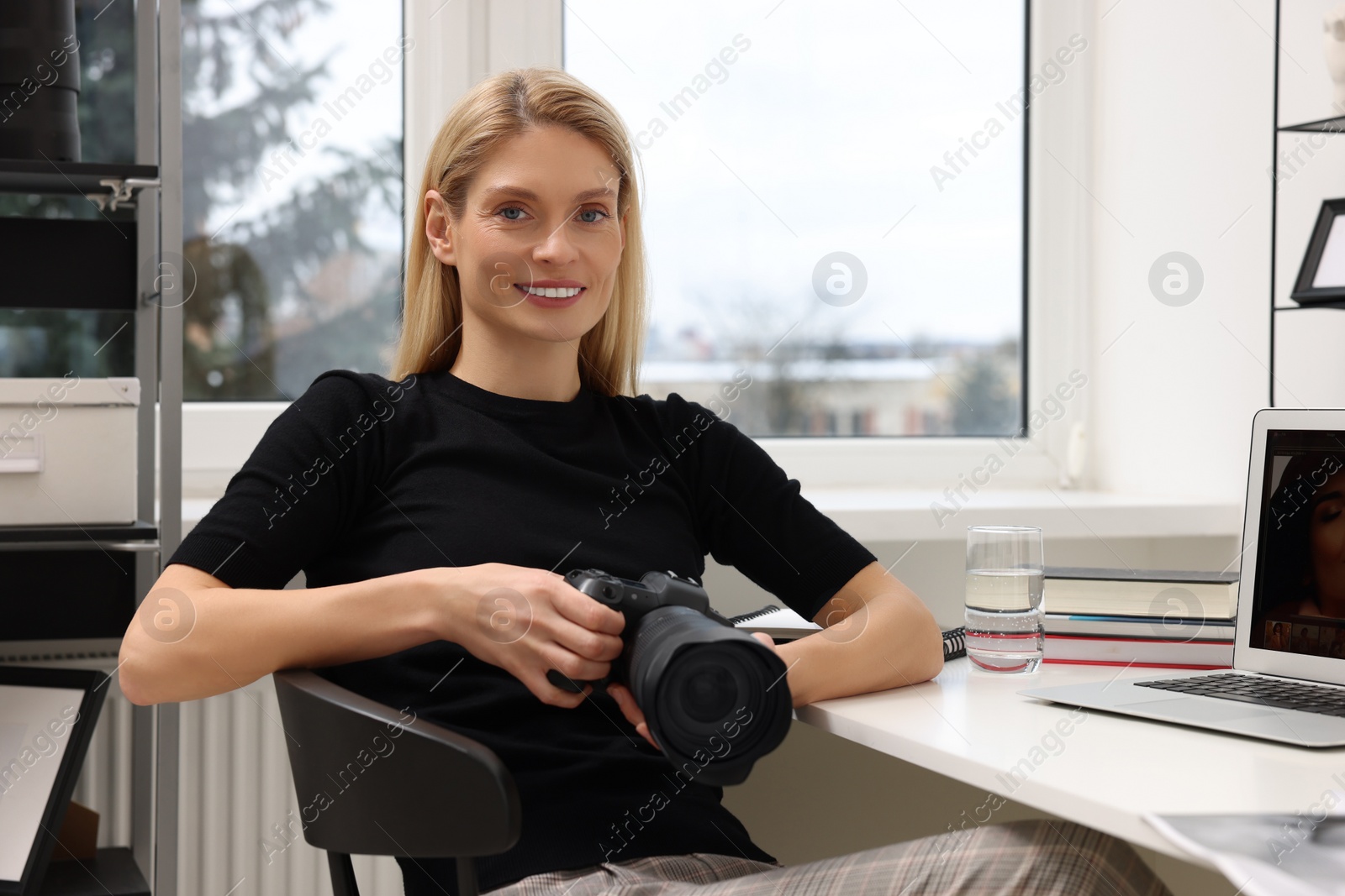 Photo of Professional photographer with digital camera at table in office