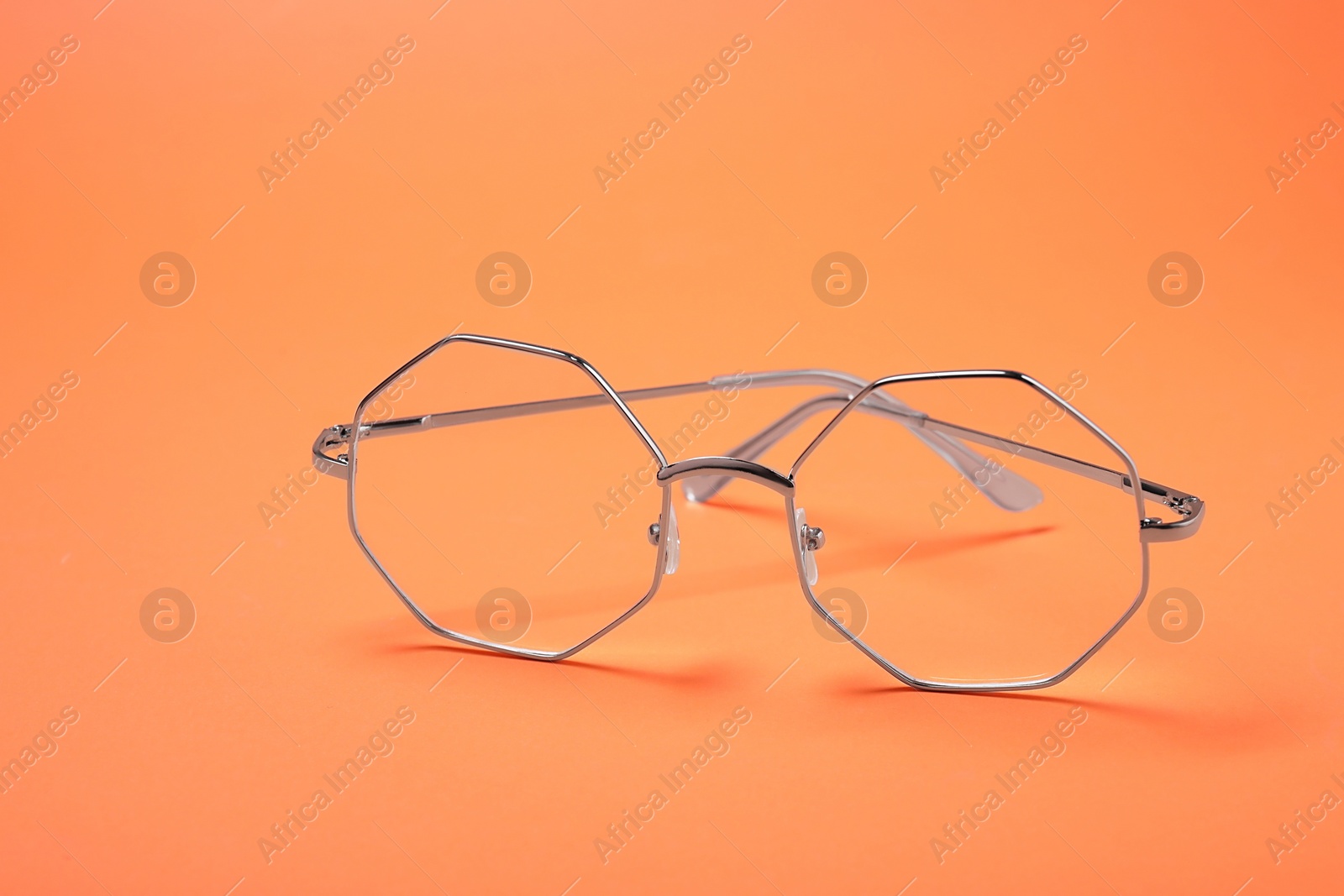 Photo of Glasses in stylish frame on orange background