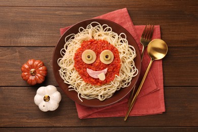 Photo of Plate with funny monster made of tasty pasta served on wooden table, flat lay. Halloween food