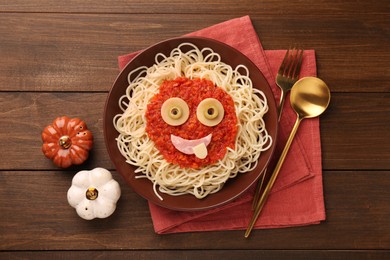 Plate with funny monster made of tasty pasta served on wooden table, flat lay. Halloween food