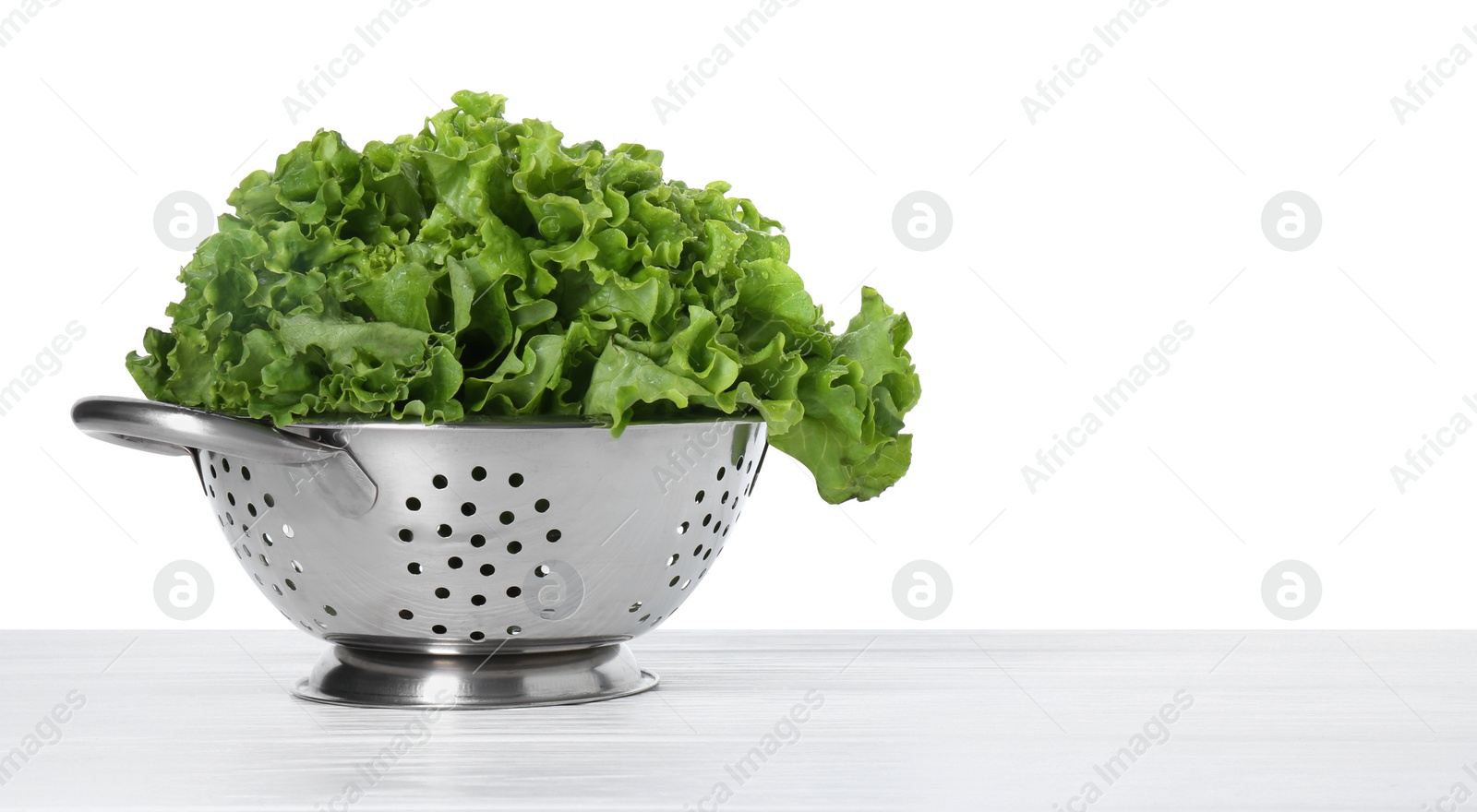 Photo of Metal colander with fresh lettuce on table against white background, space for text