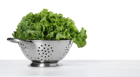 Photo of Metal colander with fresh lettuce on table against white background, space for text