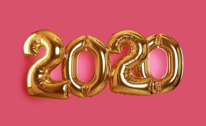 Golden balloons for party decoration on pink background. 2020 New Year celebration