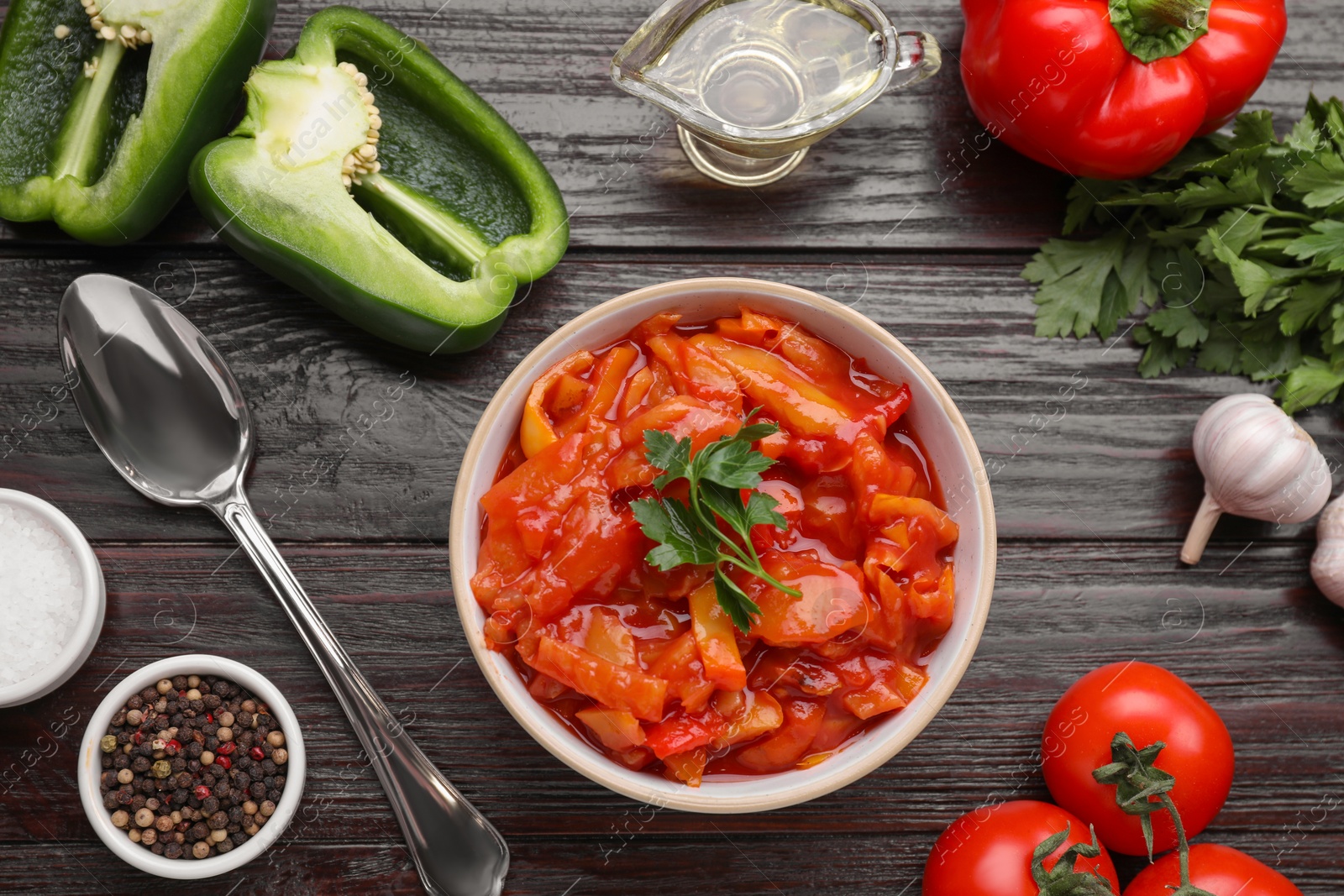 Photo of Delicious lecho and ingredients on black wooden table, flat lay