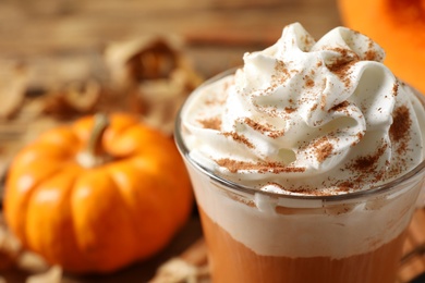 Photo of Delicious pumpkin latte with whipped cream on table, closeup