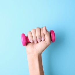 Woman holding vinyl dumbbell on color background, closeup