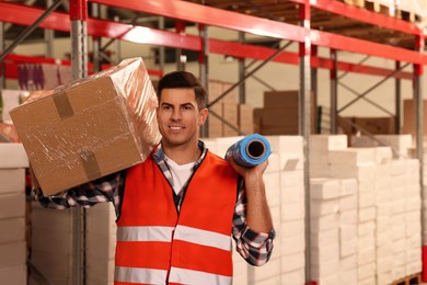 Photo of Worker with roll of stretch film and wrapped box in warehouse