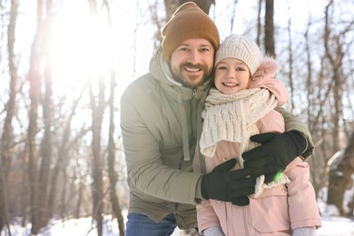 Photo of Family portrait of happy father and his daughter in sunny snowy forest. Space for text