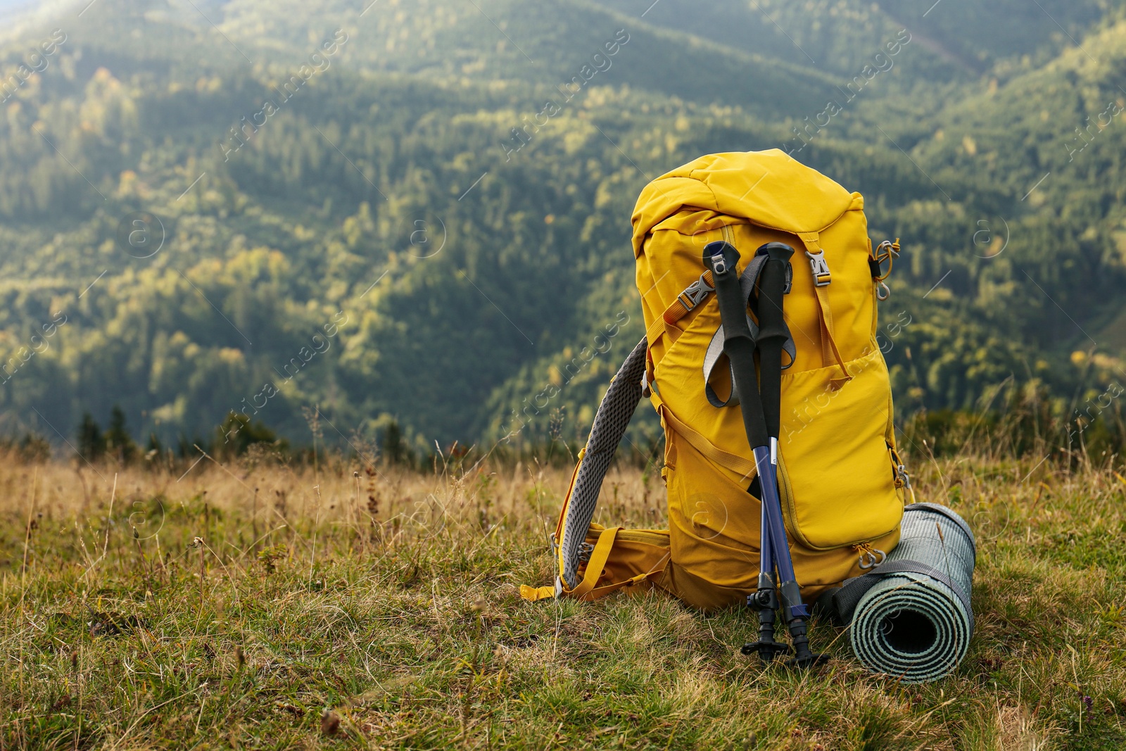 Photo of Backpack, trekking poles and sleeping mat in mountains, space for text. Tourism equipment