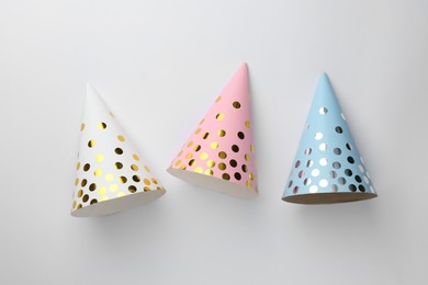 Colorful party hats on light background, top view