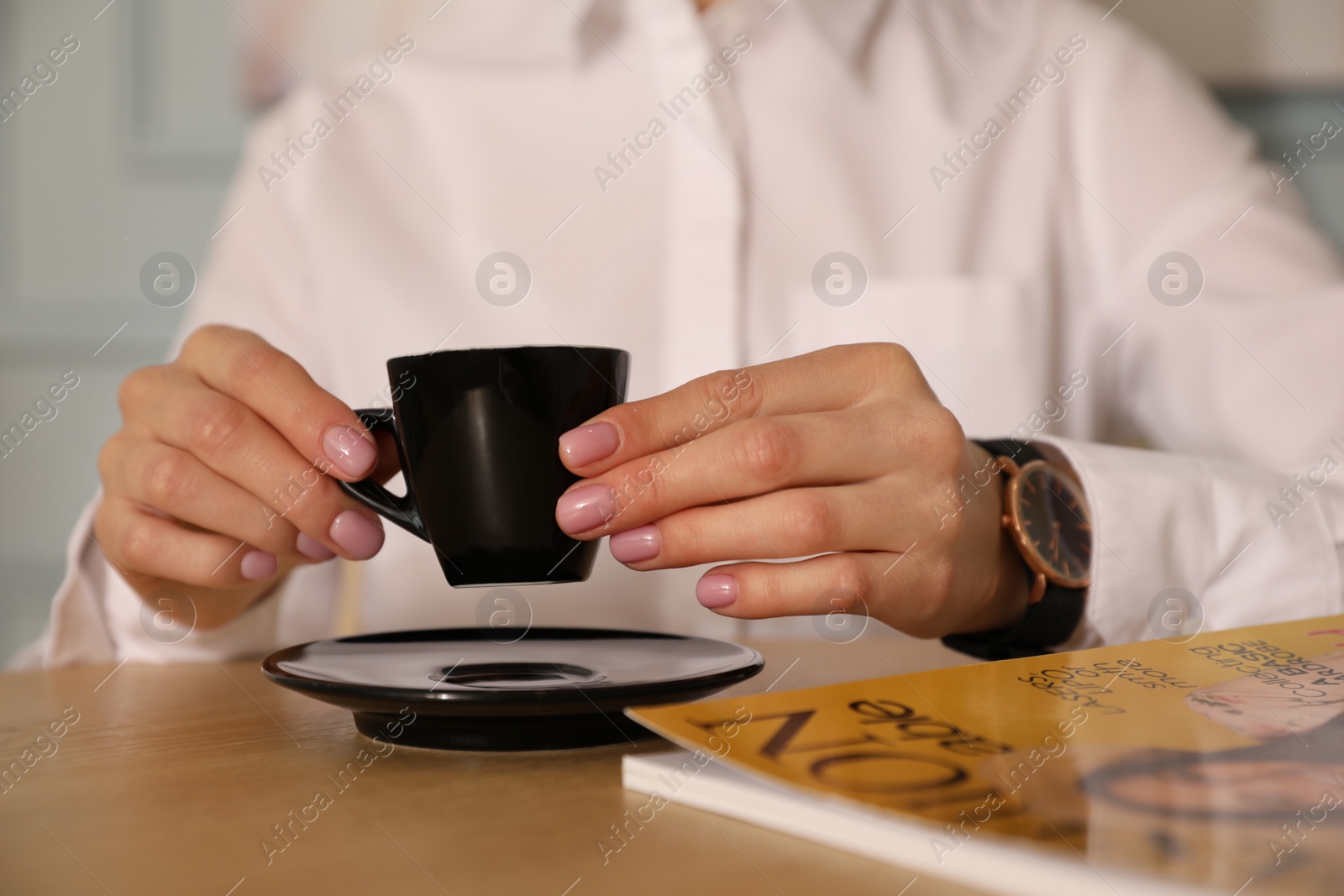 Photo of Woman with cup of coffee and magazine at cafe in morning, closeup