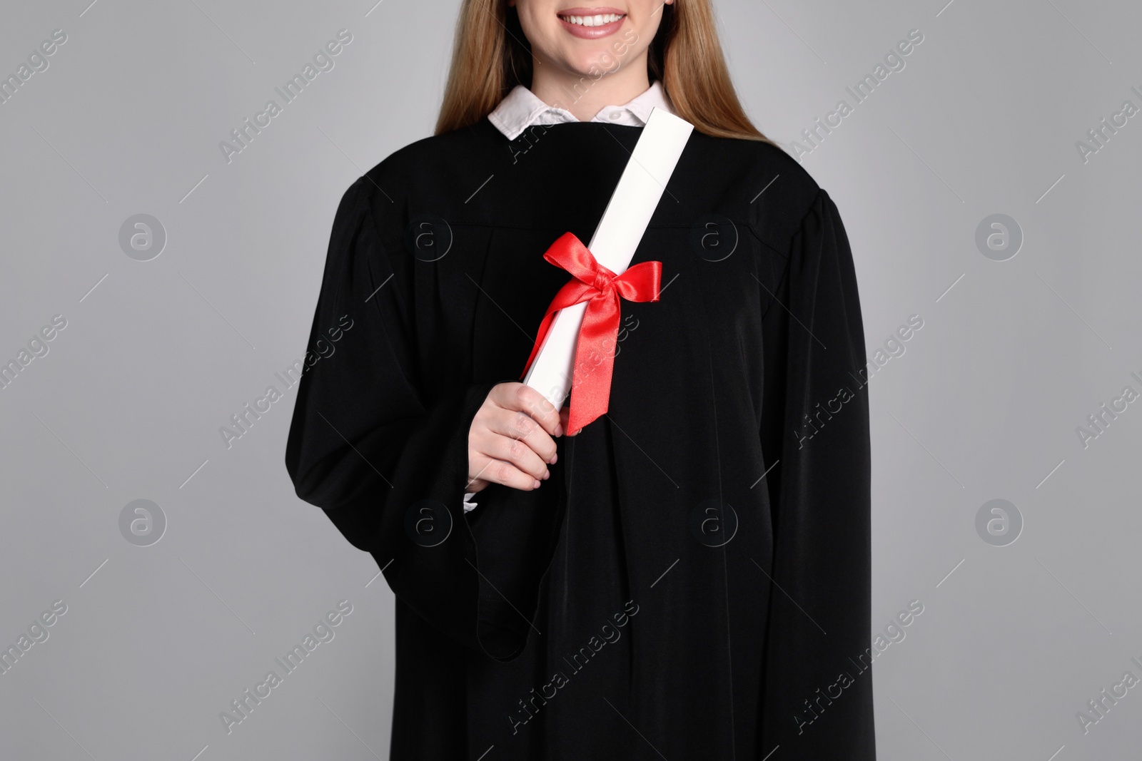 Photo of Student with diploma on grey background, closeup