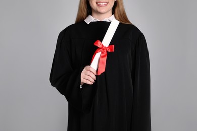 Student with diploma on grey background, closeup