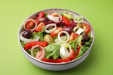 Bowl of tasty salad with leek and olives on light green table