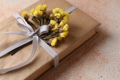 Photo of Book decorated with flowers on beige textured table, closeup