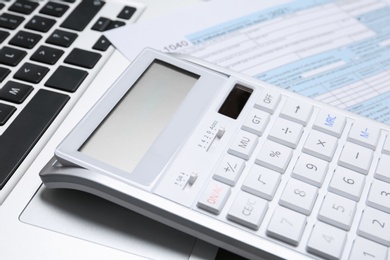 Photo of Calculator and document on laptop, closeup. Tax accounting