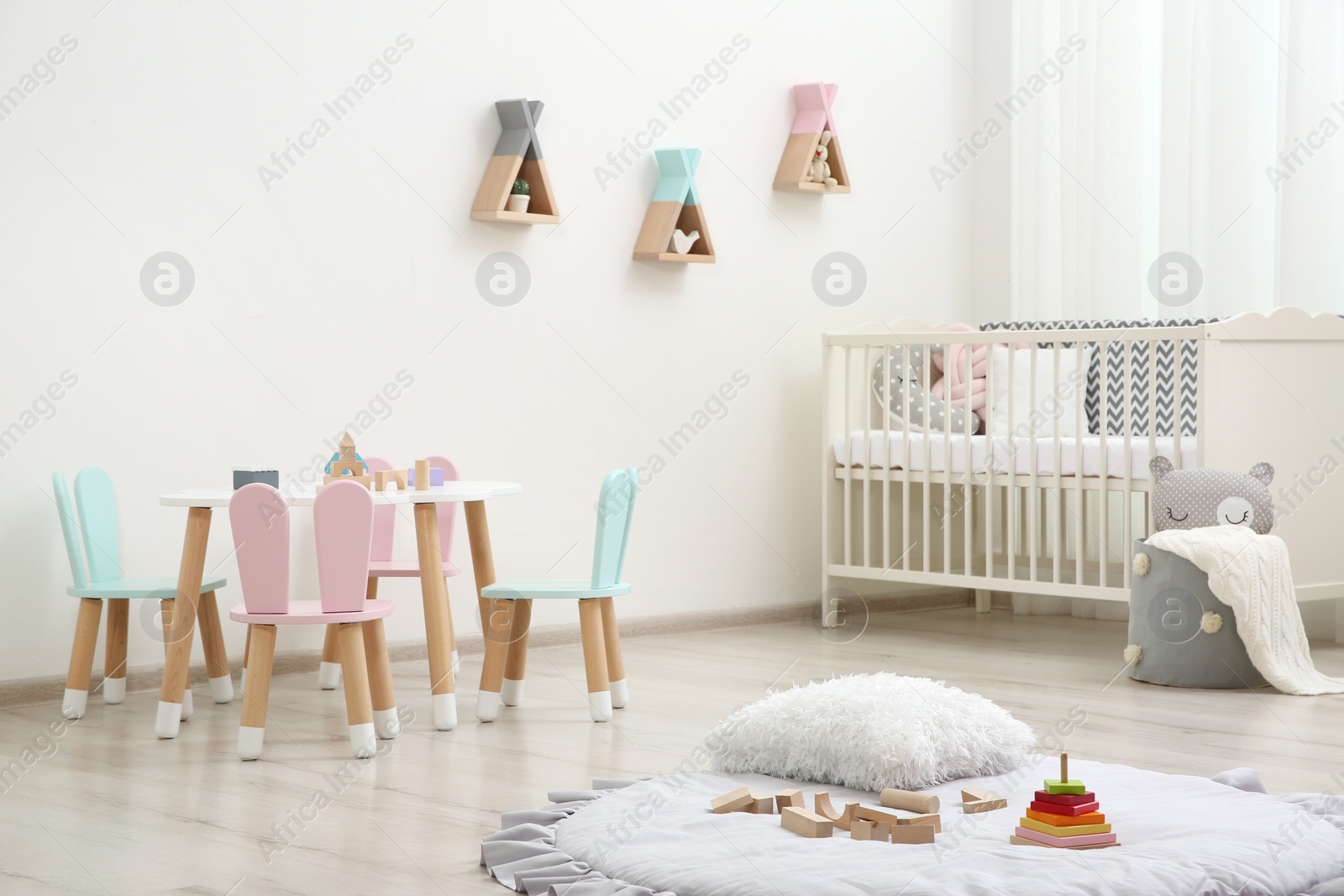 Photo of Cute baby room interior with cot and little table