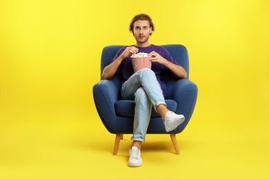 Photo of Man with popcorn sitting in armchair during cinema show on color background