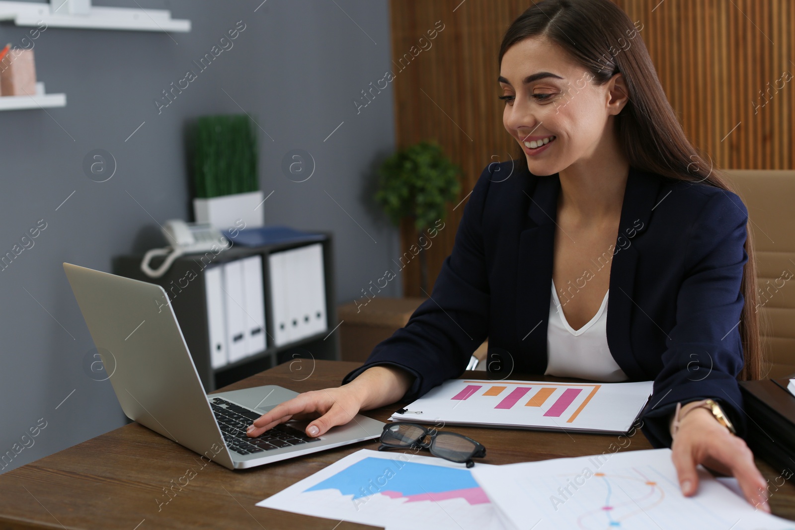 Photo of Businesswoman working with laptop and documents at table in office