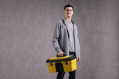 Young man with tool box on grey background