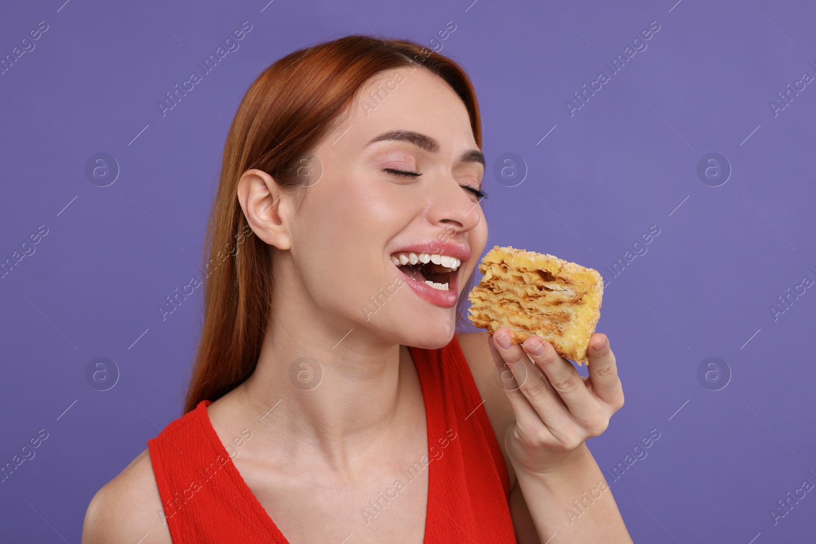 Photo of Young woman eating piece of tasty cake on purple background