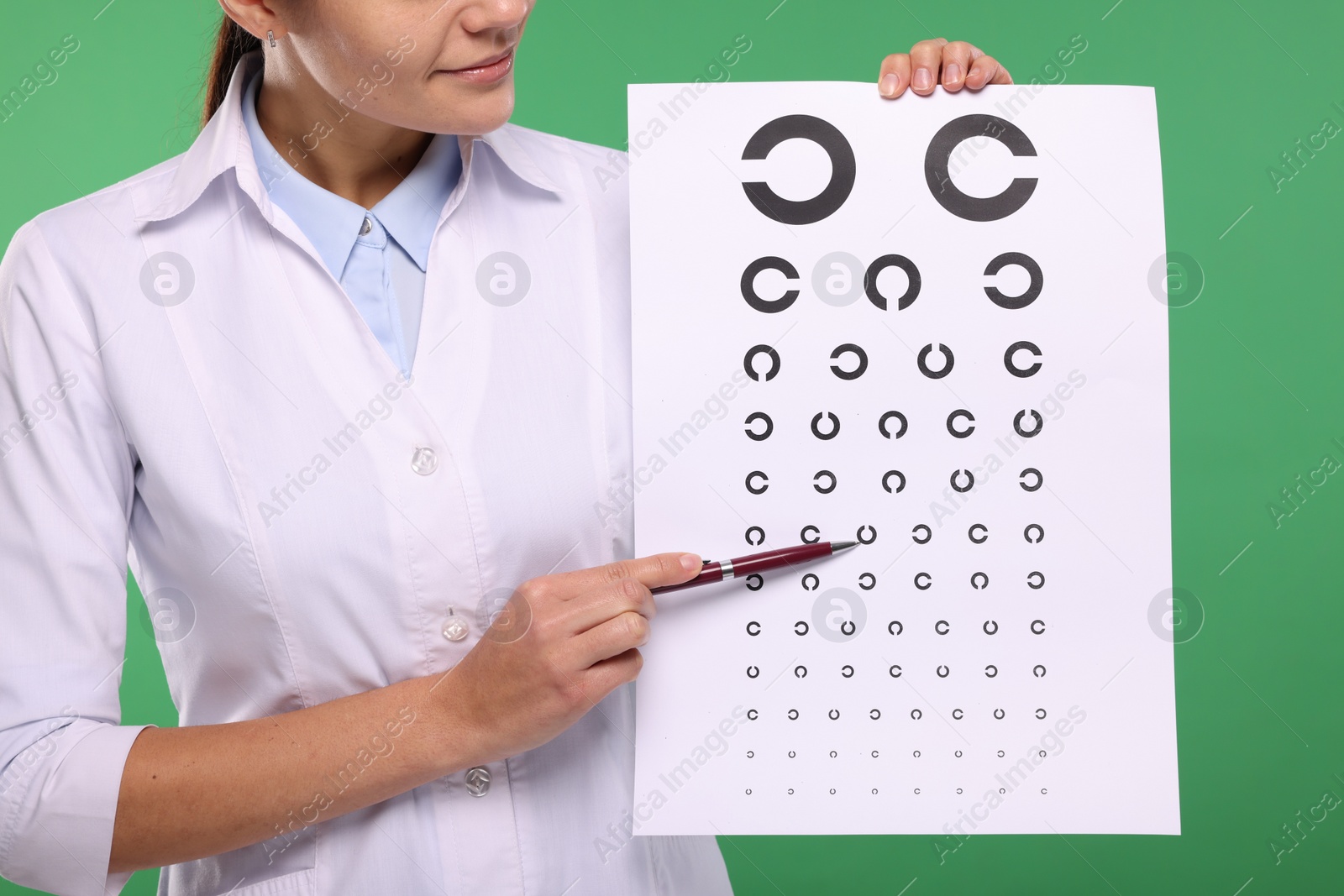 Photo of Ophthalmologist pointing at vision test chart on green background, closeup