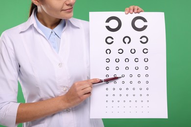 Photo of Ophthalmologist pointing at vision test chart on green background, closeup