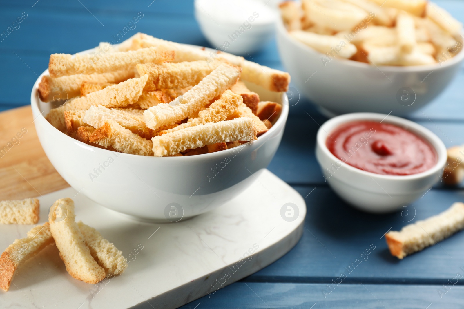 Photo of Delicious hard chucks with ketchup on blue wooden table