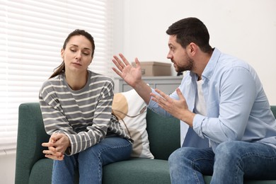 Photo of Offended wife ignoring her angry husband indoors. Relationship problems